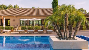 A pool area with lounge chairs and a building with a tiled roof. - Villa Monte Rei 9 in Vila Nova de Cacela (Vila Real Santo Antonio)