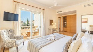 A hotel room with a large bed, a chair, a desk, a TV, and a sliding glass door to the balcony. - Villa Monte Rei 9 in Vila Nova de Cacela (Vila Real Santo Antonio)