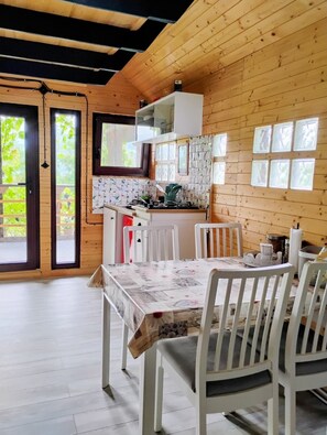 A wooden interior with a dining table, chairs, a kitchen area, and a view through the door. - 479 Tiny House, Domeniul von Agodt (Bradu)