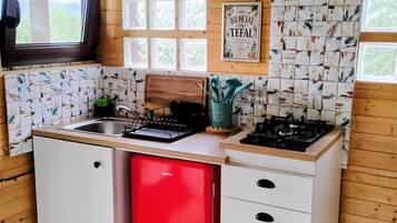 Una cocina compacta con lavavajillas rojo, armarios blancos y salpicadero de azulejos.