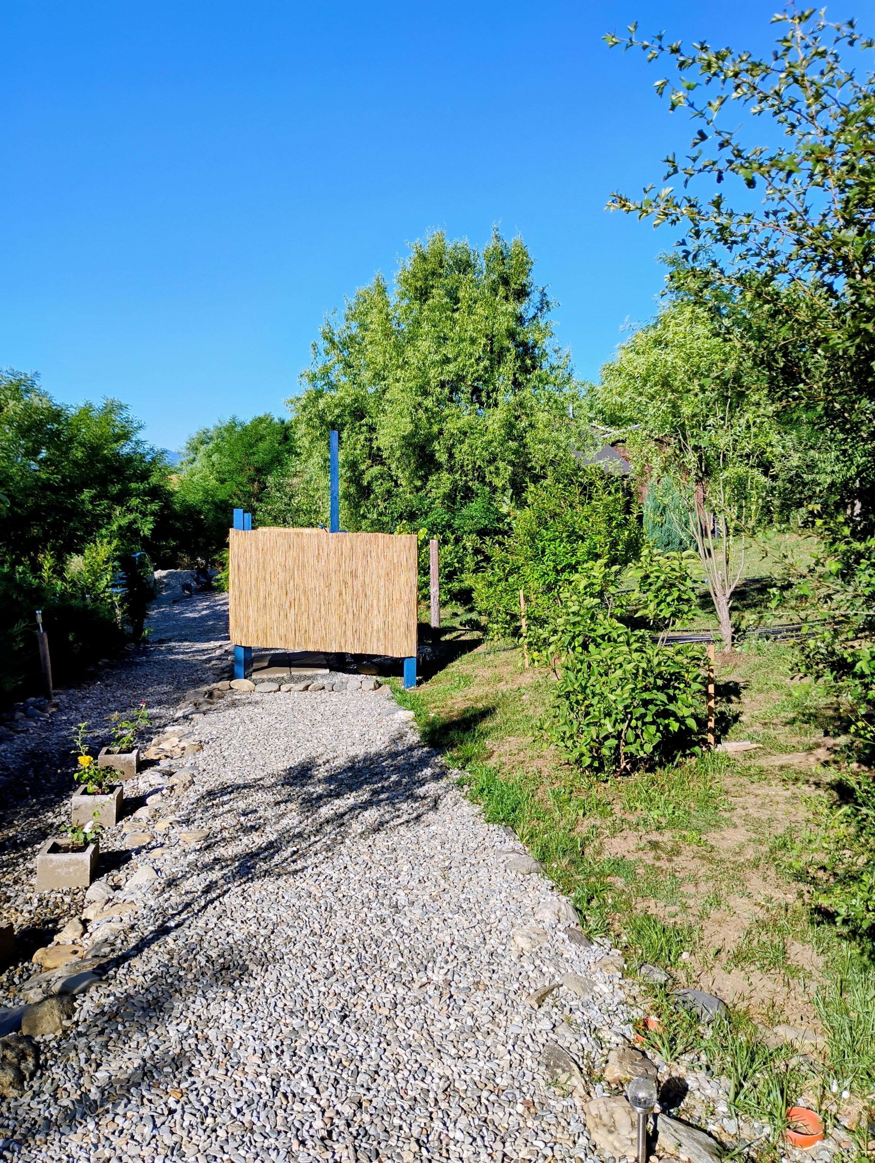Un sendero de grava con una cerca de madera y un poste azul.