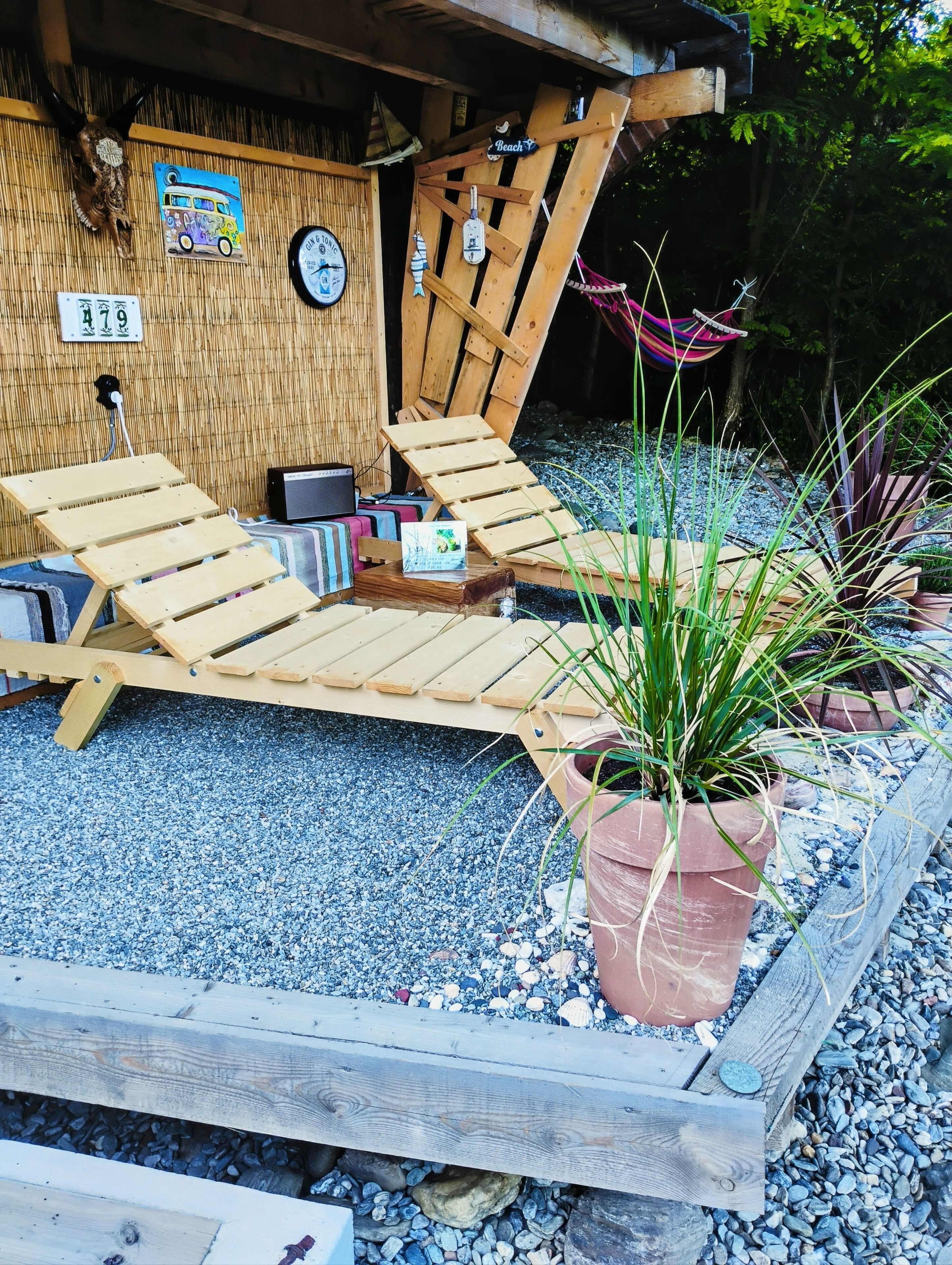 A wooden deck with lounge chairs, a small table, and a clock on the wall.