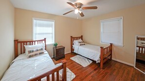 A bedroom with two single beds, a ceiling fan, wooden flooring, and a nightstand with a plant. - Marietta 2BR Close to Atlanta! (Marietta)