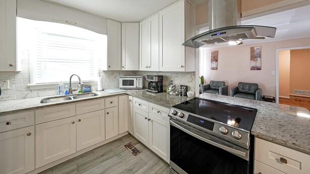 A modern kitchen with white cabinets, a black stove, a microwave, and a sink. - Marietta 2BR Close to Atlanta! (Marietta)