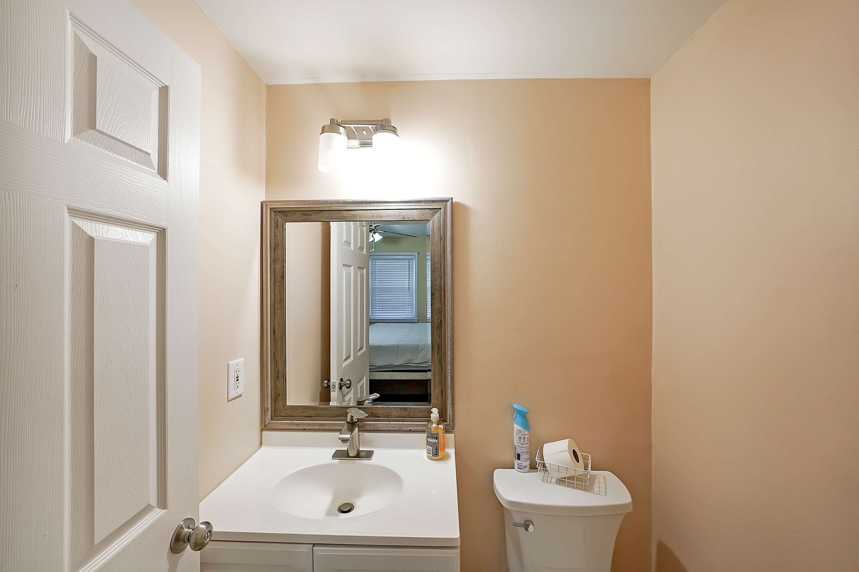 Un baño con lavamanos blanco, espejo y retrete.