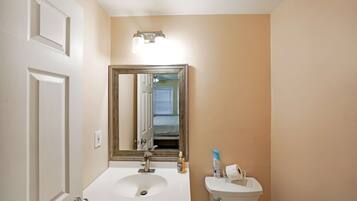 Un baño con lavamanos blanco, espejo y retrete.