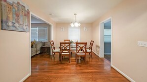 A dining area with a wooden table and chairs, a chandelier, and a painting on the wall. - Marietta 2BR Close to Atlanta! (Marietta)