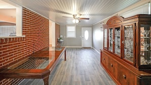 A hallway with a wooden floor, a brick wall, and a wooden cabinet with glass doors. - Marietta 2BR Close to Atlanta! (Marietta)