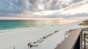 En strand med ett trästaket och utsikt över havet.
