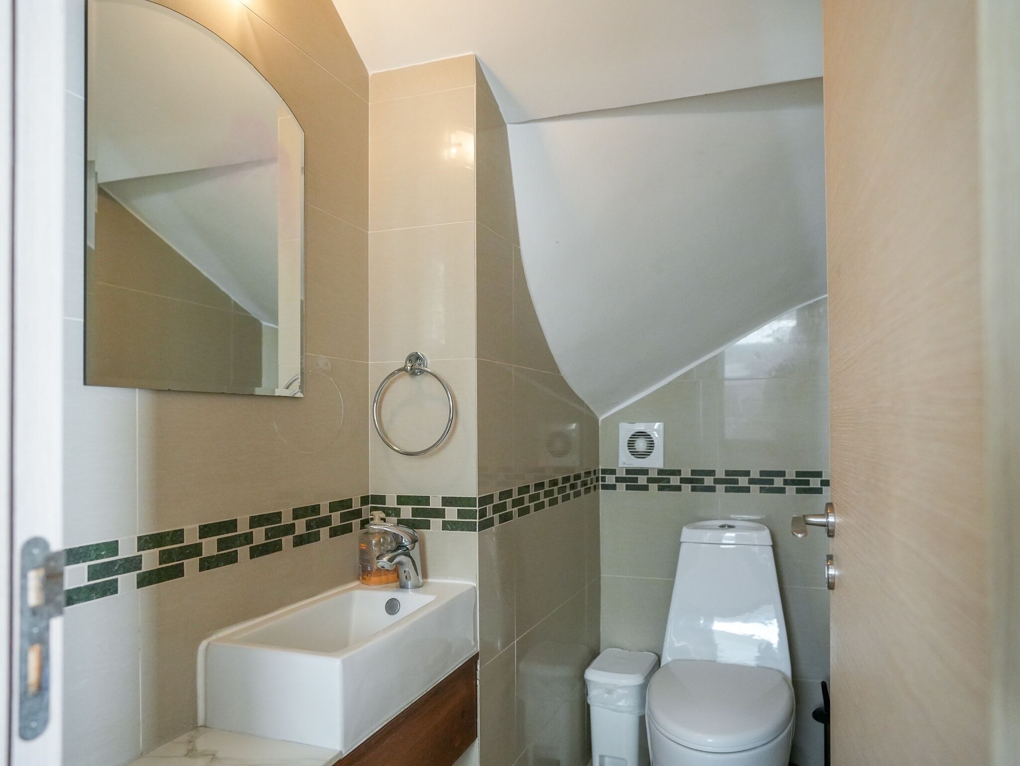 Un bagno con lavandino, specchio, porta asciugamani, servizi igienici e un piccolo cestino.