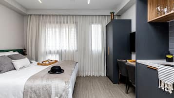 A modern hotel room with a large bed, a desk, and a television.