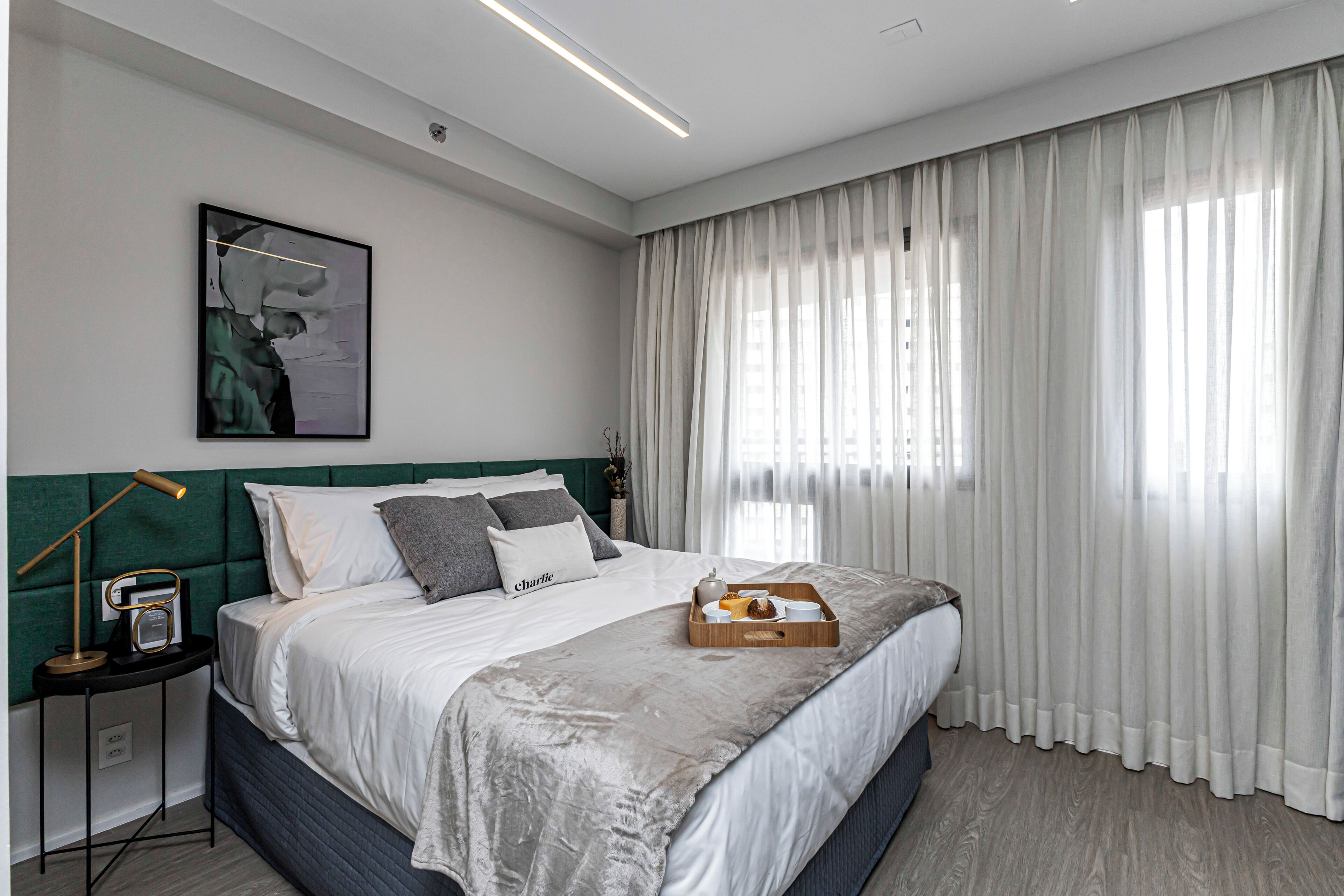 A modern bedroom with a large bed, a bedside table with a lamp, and a framed picture on the wall.