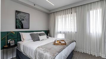 Et moderne soveværelse med en stor seng, et natbord med lampe, og et billede i ramme på væggen.