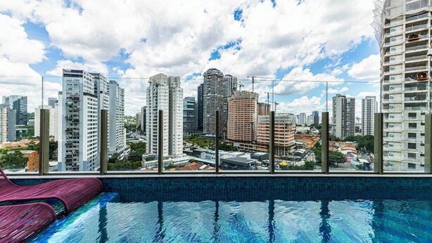 A rooftop pool with a cityscape view, surrounded by high-rise buildings. - Charlie Atmosfera Santo Amaro (São Paulo)