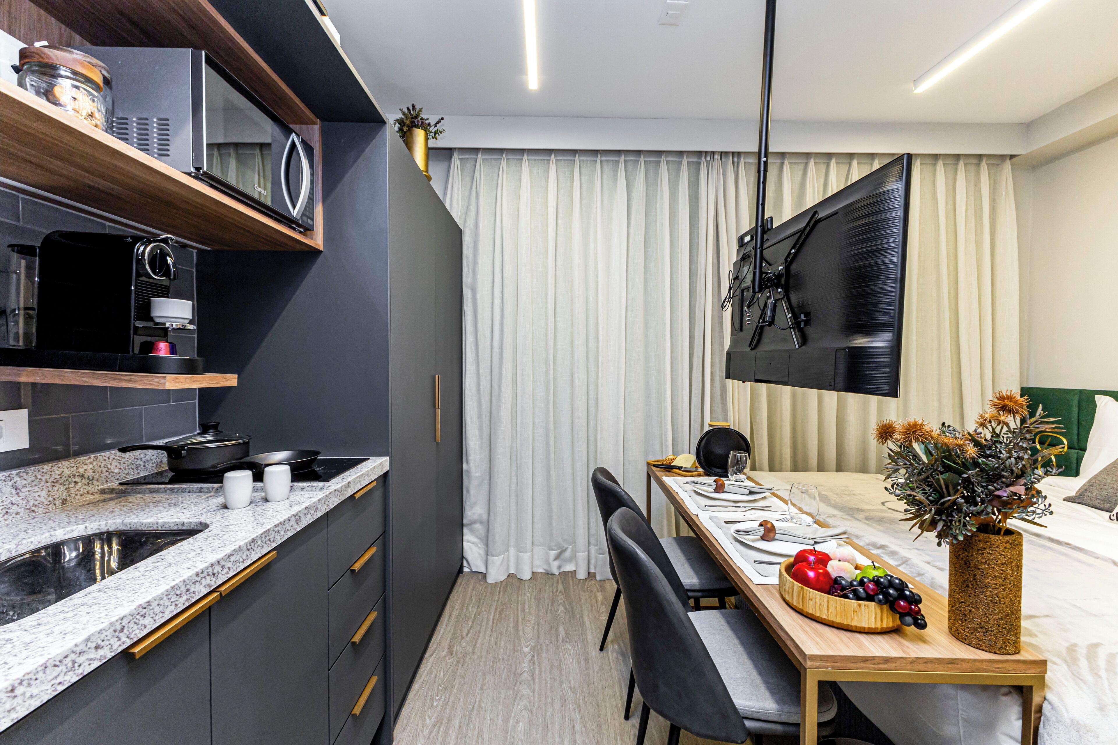A modern kitchen with a microwave, stove, and coffee maker. There is a dining area with a table, chairs, and a vase of flowers.