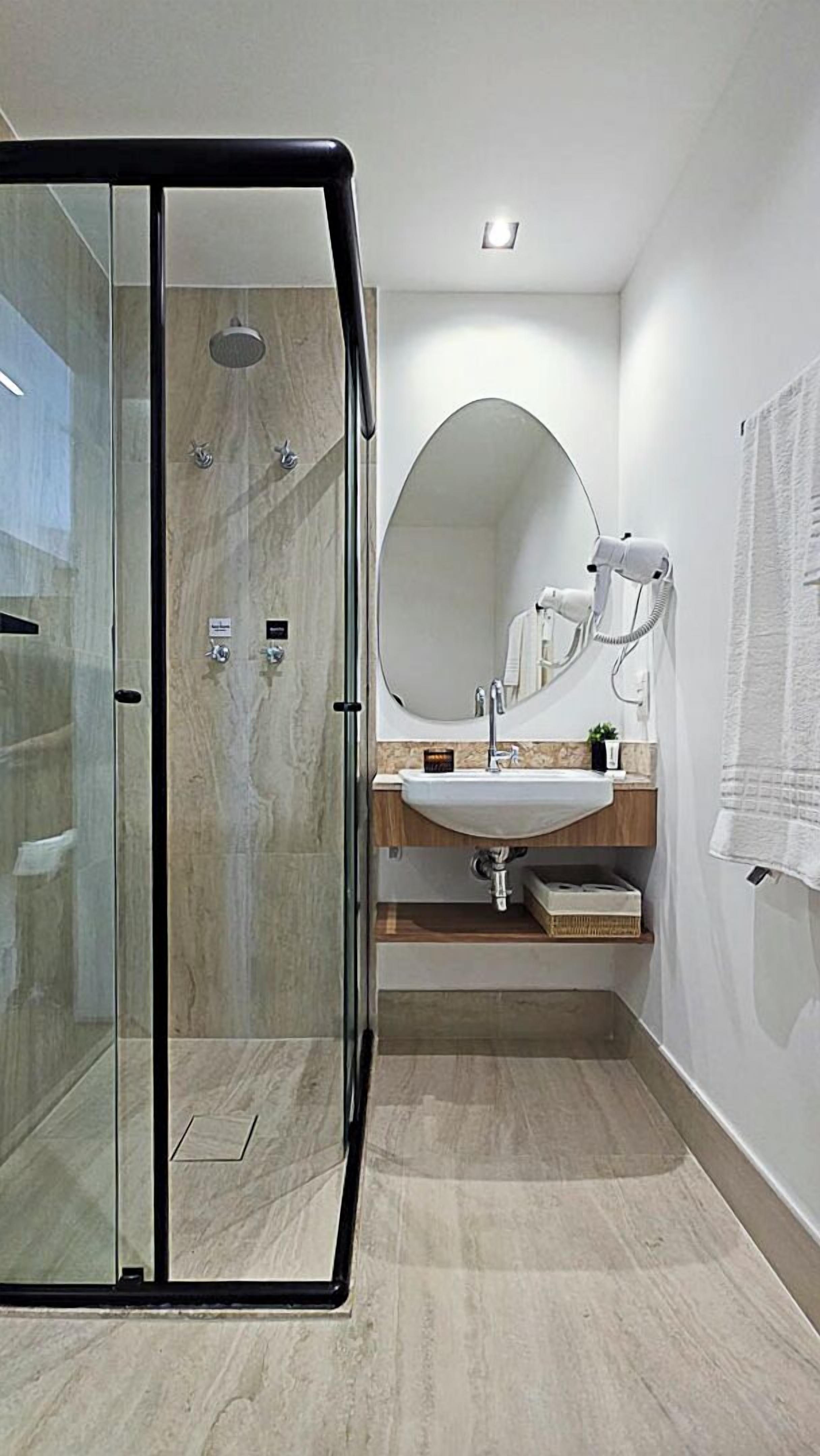 A modern bathroom with a glass-enclosed shower, a round mirror, and a sink with a wooden countertop.