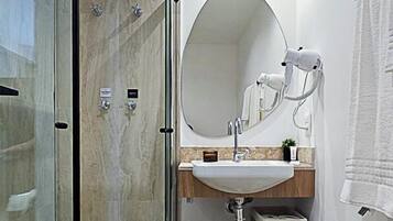 A modern bathroom with a glass-enclosed shower, a round mirror, and a sink with a wooden countertop.