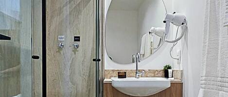 A modern bathroom with a glass-enclosed shower, a round mirror, and a sink with a wooden countertop.