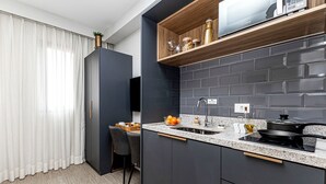 A modern kitchen with dark cabinetry, a granite countertop, and a built-in microwave. - Charlie Atmosfera Santo Amaro (São Paulo)