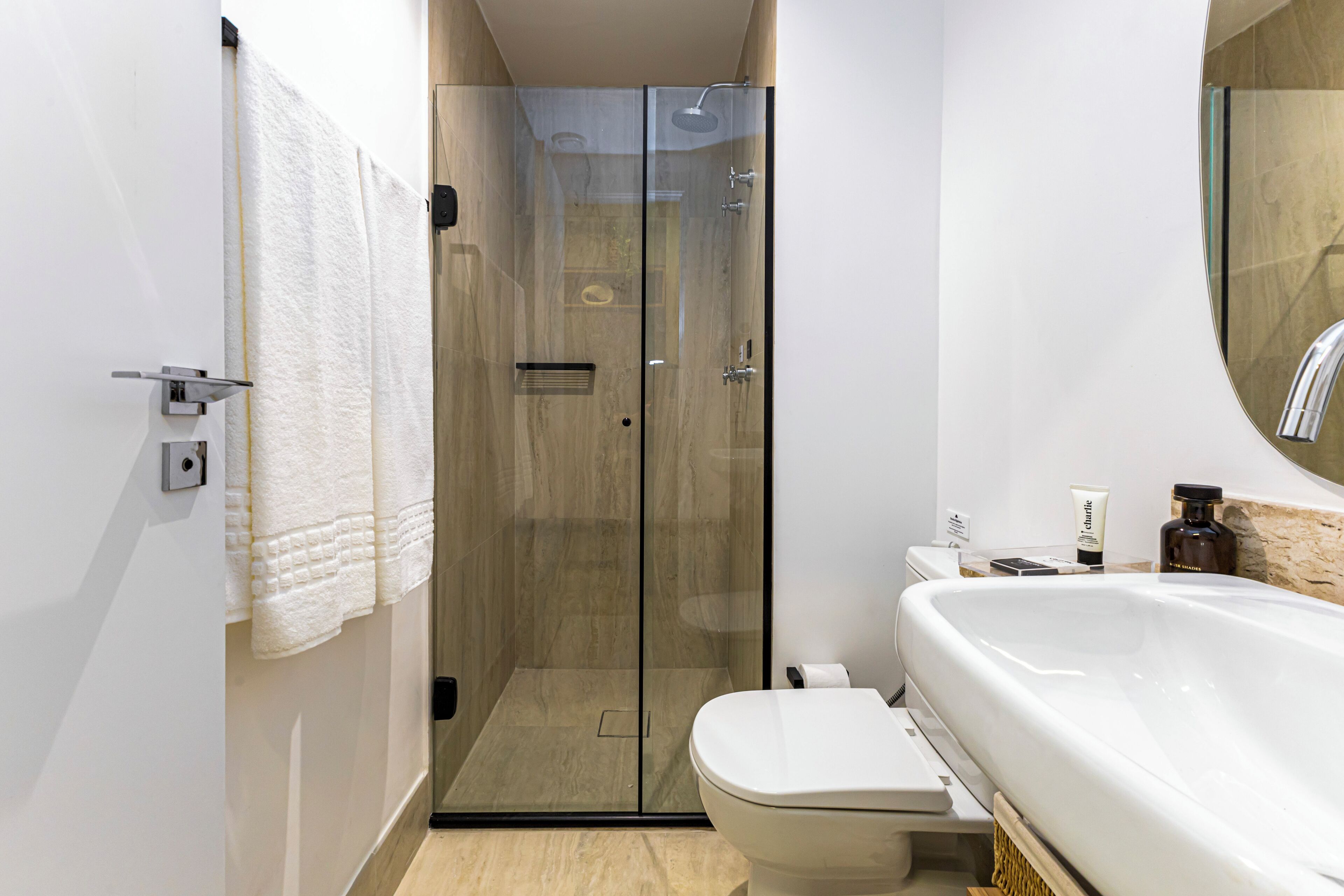 Un baño moderno con ducha de vidrio, inodoro blanco y un lavamanos grande.