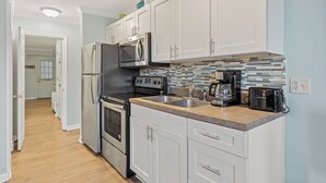 Una cocina moderna con armarios blancos, electrodomésticos de acero inoxidable, salpicadero de azulejos y encimera de madera.