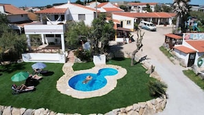 A residential area with a swimming pool, houses, and a palm tree. - Da Silva Surfcamp Bedroom Abelheira for 3 persons (Lourinhã)