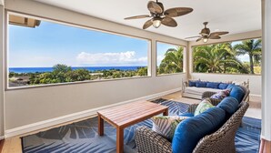 A balcony with wicker furniture, a wooden table, and ceiling fans.