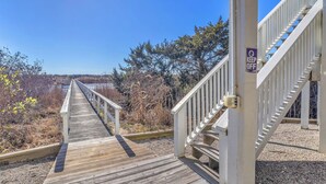 A wooden boardwalk leading to a white staircase with a 'KEEP OFF' sign. - The Loggerhead: Oceanfront, Beautiful Walkway Over Marsh (Oak Island)