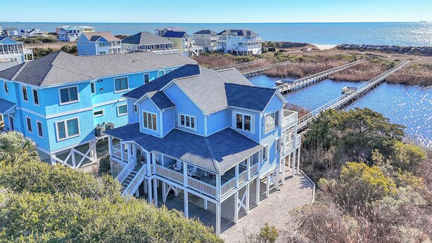 A coastal house with multiple levels, a dock, and a view of the ocean. - The Loggerhead: Oceanfront, Beautiful Walkway Over Marsh (Oak Island)