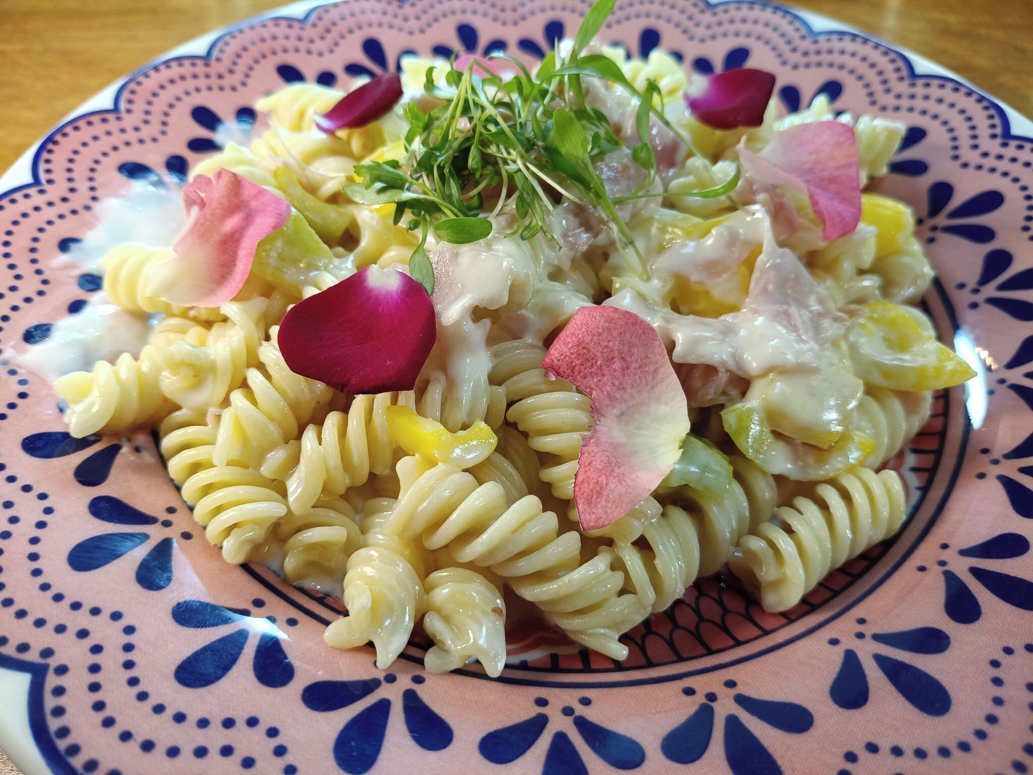 A plate of pasta with vegetables and a decorative flower.