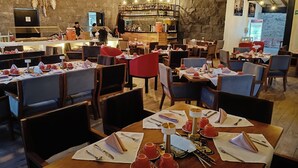 A restaurant with wooden tables and chairs, a bar area, and a stone wall.