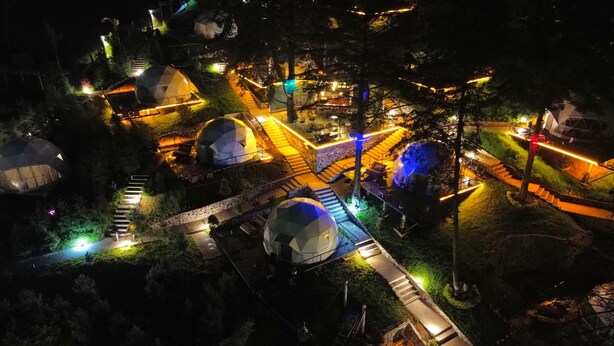 A nighttime aerial view of a resort with multiple dome-shaped accommodations, interconnected pathways, and outdoor seating areas.