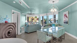 A spacious dining area with a glass table and patterned chairs, a ceiling fan, and a view of the outdoors. - Pool and Beach View from 3 Balconies (Miramar Beach)