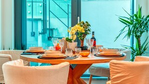 Ein Esstisch, gedeckt mit Tellern, Schüsseln, Gläsern und einer Blumenvase.