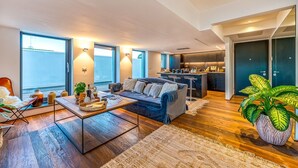 Ein modernes Wohnzimmer mit einer Couch, einem Couchtisch und großen Fenstern.