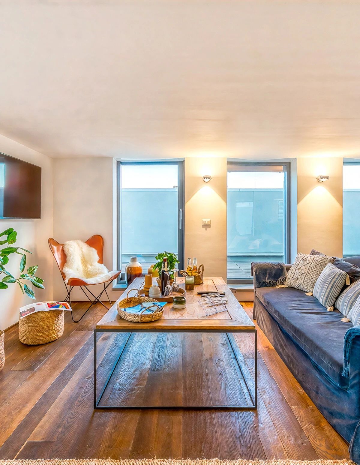 A modern living room with a sofa, a coffee table, a TV, and a large window.