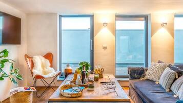 A modern living room with a sofa, a coffee table, a TV, and a large window.