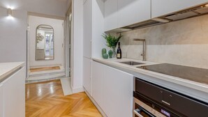 Una cocina moderna con armarios blancos, un lavamanos de acero inoxidable y un lavavajillas integrado.