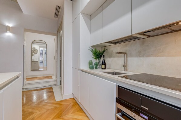 Een moderne keuken met witte kasten, een roestvrijstalen spoelbak en een inbouwvaatwasser.