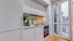 Una cocina moderna con armarios blancos, horno integrado y un ventanal con vista a la ciudad.
