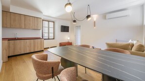 Une cuisine moderne avec des meubles en bois, une table à manger avec des chaises et des luminaires suspendus.