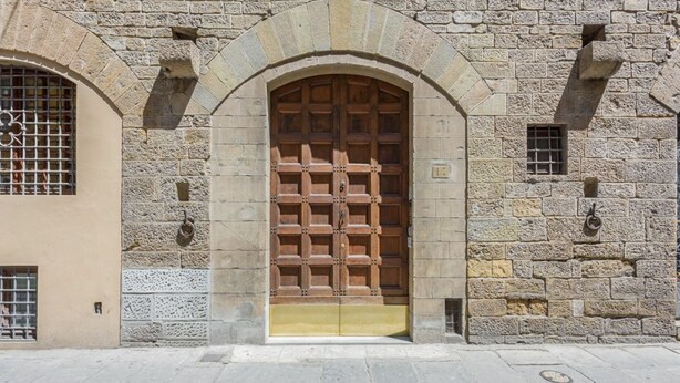 Un bâtiment en pierre doté d’une grande porte en bois et de fenêtres en arc de cercle.