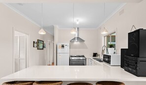 Een moderne keuken met witte kasten, een centraal eiland, een fornuis, oven, magnetron en een zwarte koelkast.