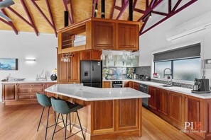 A spacious kitchen with wooden cabinets, a large island, and bar stools.
