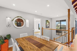 A modern dining area with a wooden table, white chairs, and a decorative mirror. - Amazing Location with Ocean View (Cowes)
