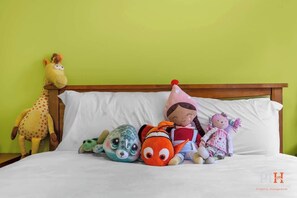 Ein Bett mit Kuscheltieren und einer Giraffe vor einer grünen Wand.