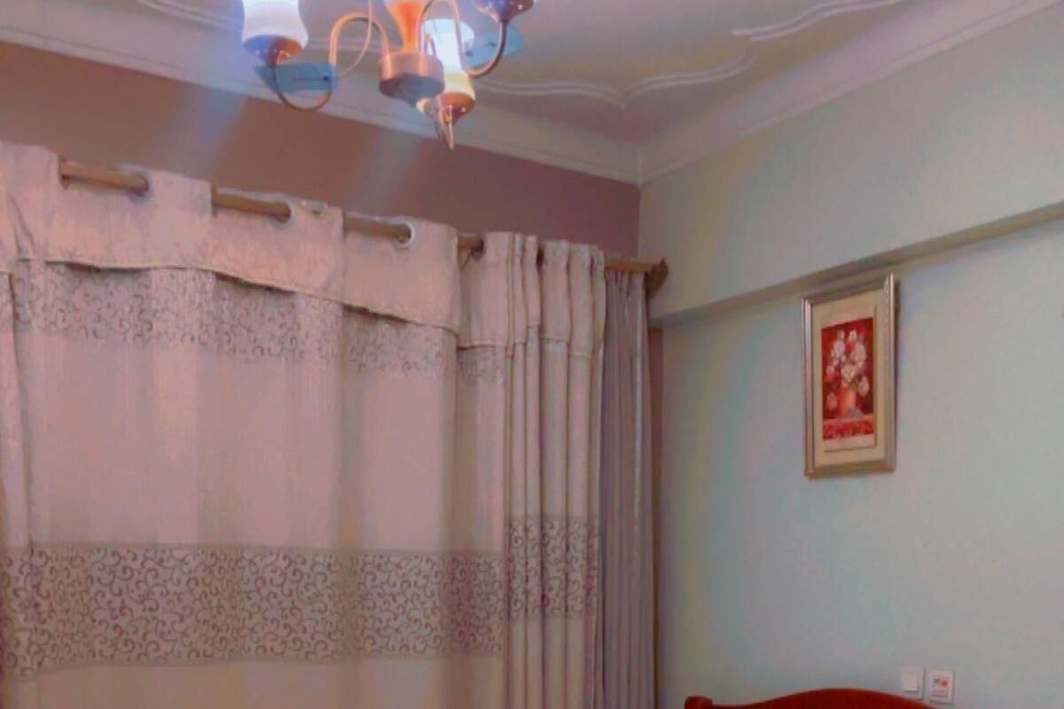 A neatly made bed with a wooden headboard, a single bedside table, and a wall-mounted light fixture.