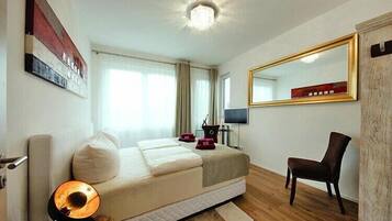 Een hotelkamer met een bed, een stoel, een televisie en een spiegel.