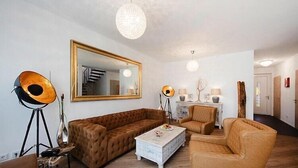 A living room with a large mirror, a brown sofa, a white coffee table, and a floor lamp. - Apartment mit Frühstück in Strausberg (Strausberg)