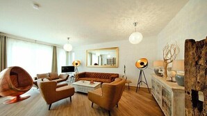 A modern living room with a sofa, armchairs, a coffee table, a hanging chair, and a large mirror. - Appartement in Strausberg mit Frühstück inklusive (Strausberg)